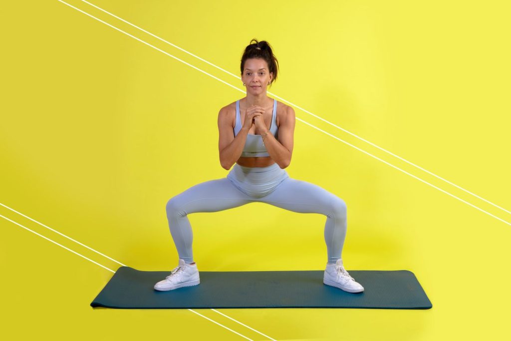 Female athlete doing sumo squats to show what do sumo squats work in a lower-body workout.
