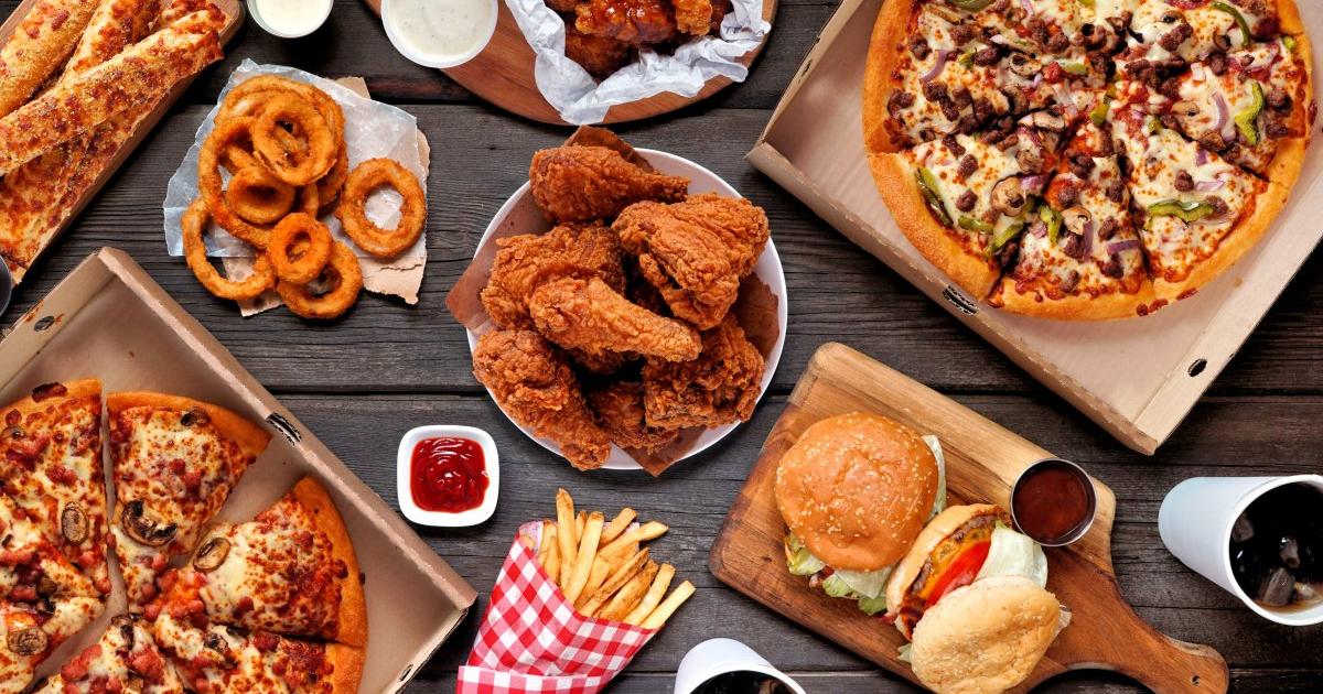 A table filled with burgers, fries, chicken, and drinks from the best fast food restaurants.